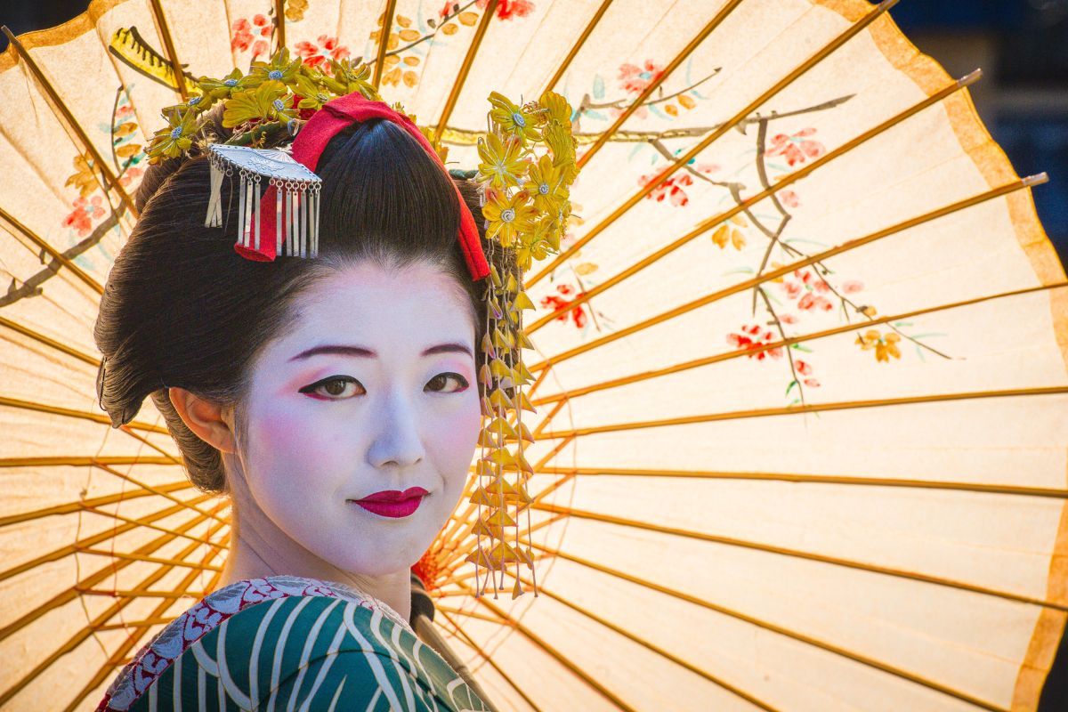 Geisha vestita di kimono rosso in posa nel giardino zen